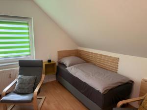 ein kleines Schlafzimmer mit einem Bett und einem Stuhl in der Unterkunft Pension Hettstedt in Hettstedt + 20 Fotos