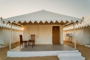 a tent with a table and chairs in it at Shreeji Desert Resort in Sām