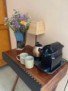 a coffee maker on a table with a vase of flowers at La Fermette Champenoise in Jonquery
