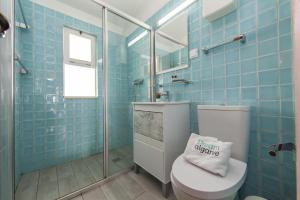 a blue tiled bathroom with a toilet and a glass shower at Calheta House in Luz in Luz +26 photos