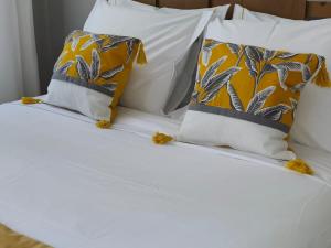 a bed with white sheets and yellow and gray pillows at Mourisca 1810 Guest House in Águeda