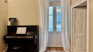 Una habitación con un piano y una puerta con cortinas. en Cuneo Charme, en Cuneo