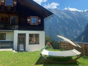 a hammock in front of a house with mountains at Alpenchalet Königreich Innerböden in Ginzling
