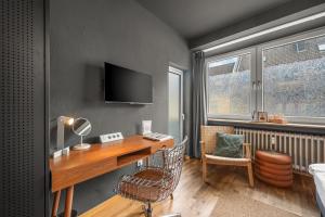 Zimmer mit einem Schreibtisch, einem Stuhl und einem TV in der Unterkunft MedienHafen Designer Studio in Düsseldorf