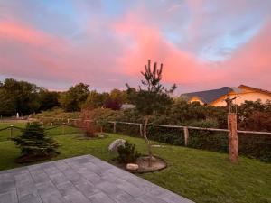 Un jardín con un árbol y una valla al atardecer. en Ferienhaus NILO, en Nisdorf