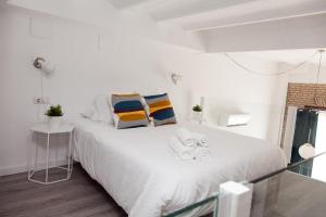 a white bedroom with a large white bed with pillows at GoToSeville FERIA APARTMENTS in Seville