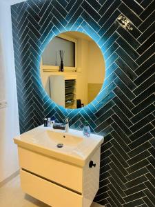 ein Badezimmer mit einem runden Spiegel über einem Waschbecken in der Unterkunft Moderne, gepflegte helle Neubau-Einliegerwohnung in Rohrbach