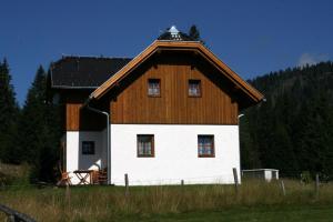 a large barn with a wooden roof on a field at Hüttendorf Flattnitz - Typ C in Flattnitz