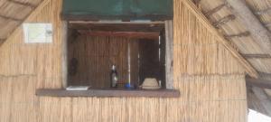 une fenêtre dans un bâtiment avec une bouteille de vin dans l'établissement Marrow camping site, à Sikwanyi