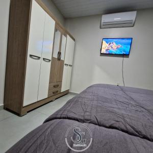 Residencia SG - Casa Duplex في انكارناسيون: غرفة نوم بها سرير وتلفزيون على الحائط
