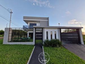 a house with a black door and green grass at Residencia SG - Casa Duplex in Encarnación