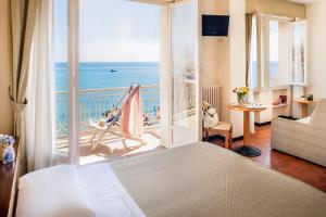 een slaapkamer met een bed en een balkon met uitzicht op de oceaan bij Hotel Golfo e Palme in Diano Marina