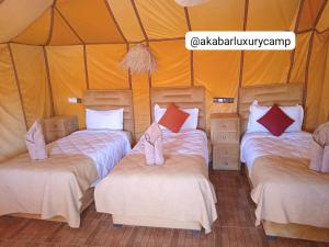 a group of three beds in a tent at Akabar Luxury Desert Camp in Merzouga