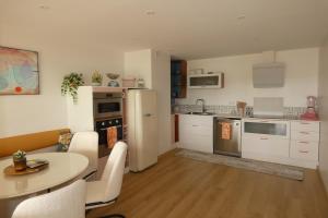 a kitchen with a table and a refrigerator at LAC CASA 60' Sixties-style flat with terrace overlooking the lake 300 m in Bilieu