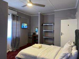a bedroom with a white bed and a television at Buffalo Bob Lodge in Livingstone