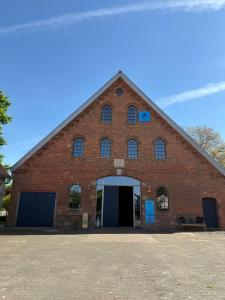 un grand bâtiment en briques rouges avec une grande porte dans l'établissement Edelhof1877, à Thedinghausen
