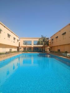 Una gran piscina frente a dos edificios. en كمباوند رومانوس فيلاجيو, en Yeda