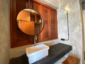 a bathroom with a white sink and a mirror at Voyage Retreat Pulau Pangkor 归航楼 in Pasir Bogak