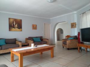 a living room with couches and a table and a tv at Rangers Airport Lodge in Benoni