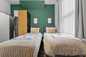 Dos camas en una habitación con paredes verdes. en NEW! 4BR 4BATH, Perfect for Contractors, Smart TVs, WiFi, en Coventry