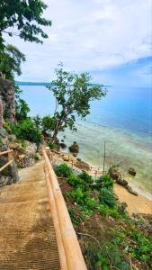 a wooden path next to the ocean with a tree at Tez's Backpacking Lodge in Maria