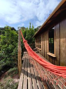 a hammock on a wooden deck next to a building at Chalé Solar no Matutu in Aiuruoca