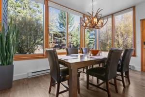 a dining room with a table and chairs and large windows at RMR: Yarrow 2311 Condo in The AspensWilson WY in Moose Wilson Road