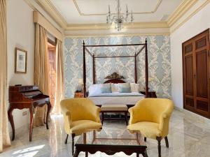 a bedroom with a bed and a piano and two chairs at Soho Boutique Duques de Medinaceli - Adults Recommended in El Puerto de Santa María