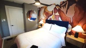 The Funky Fun Haus - Pickleball, Hot Tub, Arcade في كولومبوس: غرفة نوم بها سرير كبير ولوحة فنية على الحائط