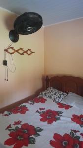 ein Schlafzimmer mit einem Bett mit einer Bettdecke mit roten Blumen in der Unterkunft Sítio fortaleza in Salvaterra