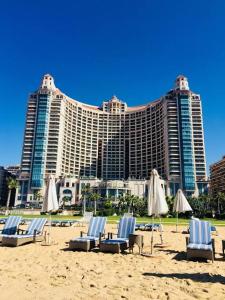 a group of chairs and umbrellas on a beach with a hotel at Luxury Sea View Apartment in Four Seasons Alexandria in Alexandria