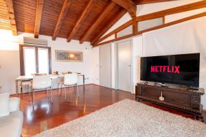 ein Wohnzimmer mit Fernseher und Tisch mit Stühlen in der Unterkunft Centralissimo vista Municipio, Elegante con Rooftop in Pordenone