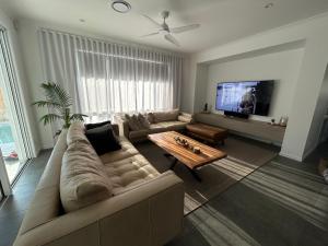 een woonkamer met een bank en een tv bij Sugar Shore Retreat in Cudgen