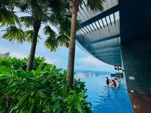 a pool with palm trees and people in the water at Eaton Delight Residences in Kuala Lumpur