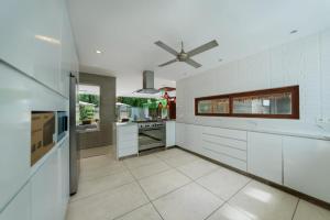 een keuken met witte kasten en een plafondventilator bij THE MUSE Pantai Nyanyi Villa in Canggu