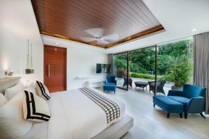 een slaapkamer met een wit bed en blauwe stoelen bij THE MUSE Pantai Nyanyi Villa in Canggu +28 foto's