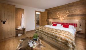ein Schlafzimmer mit einem großen Bett mit einem Hirschkopf an der Wand in der Unterkunft Bachgut Jagdhaus Chalet in Saalbach-Hinterglemm