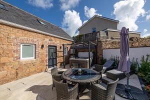 a patio with a table with chairs and an umbrella at Granite cottage in Isle of Jersey