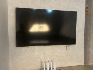 a flat screen tv on a wall with three white candles at avenue hassan 2 agadir in Oulad Akkou