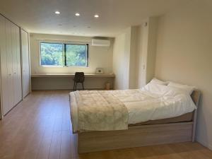 a bedroom with a large bed and a window at ゲストハウス坂の上のソルティーズ in Kainan