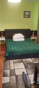 a bedroom with a bed with a green comforter and pillows at Hotel Marko 2 Warszawa in Warsaw