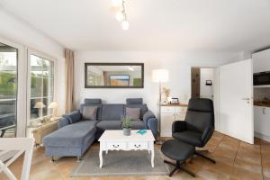 a living room with a blue couch and two chairs at Holunderbusch in Schönberger Strand