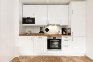 a white kitchen with white cabinets and appliances at Holunderbusch in Schönberger Strand