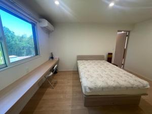 a bedroom with a bed and a window at ゲストハウス坂の上のソルティーズ in Kainan