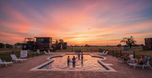 un groupe de personnes debout dans une piscine au coucher du soleil dans l'établissement New Pickleball, Cornhole, Pool, Patio & Hot Tub, à Fredericksburg