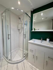 a white bathroom with a shower and a sink at D&D Emerald House Anfield in Liverpool