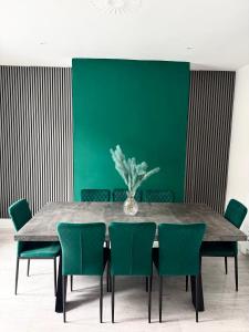 a dining room with a table and green chairs at D&D Emerald House Anfield in Liverpool +17 photos