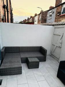 a bench sitting on a patio next to a white wall at D&D Emerald House Anfield in Liverpool