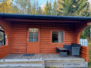 a cabin with a wooden deck with a door and a bench at Gäststuga och bastu in Oravais