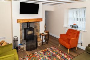 Rose Cottage, Kepwick Village with Hot Tub - Rural Location في Kepwick: غرفة معيشة بها موقد وتلفزيون بشاشة مسطحة